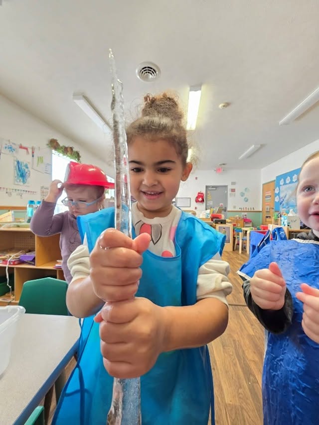 Child smiling and holding an icicle.