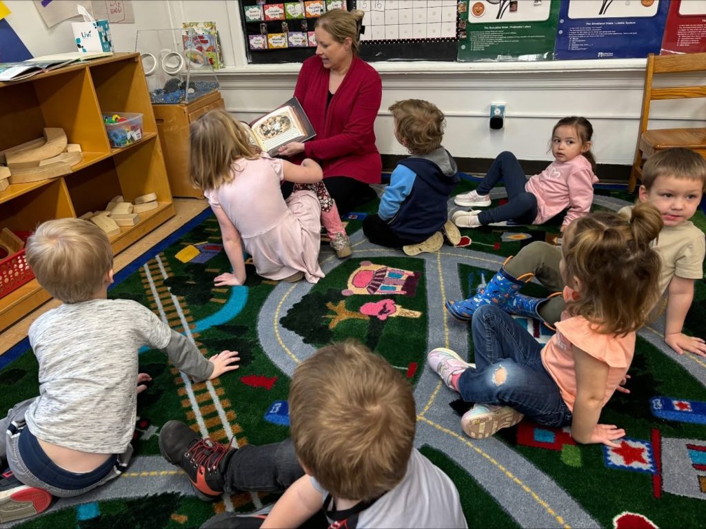 Woman reading to children in their classroom.